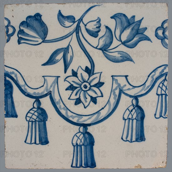 Border tile, blue on white, garland with tassels, above which is flower tendril with two tulips and other flower, vertically