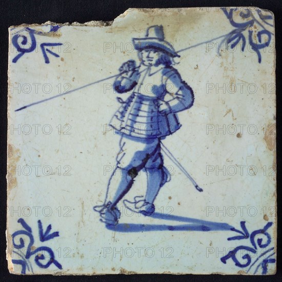 White tile with blue warrior with hat and spear over shoulder; corner pattern ox head, wall tile tile sculpture ceramic