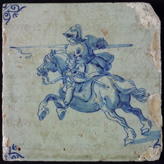 White tile with blue horseman in armor with lance; corner pattern ox head, wall tile tile sculpture ceramic earthenware glaze