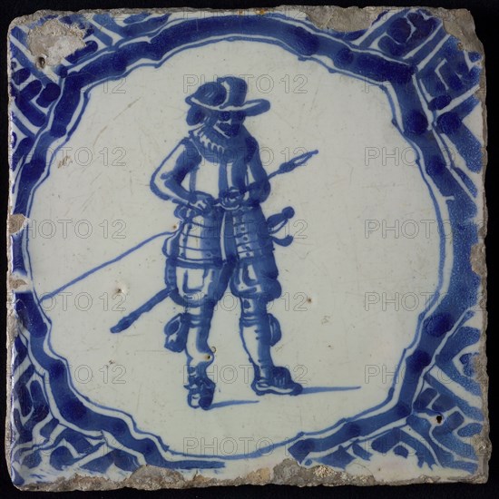 White tile with blue warrior in brace-shaped frame, corner pattern meander, wall tile tile sculpture ceramic earthenware glaze