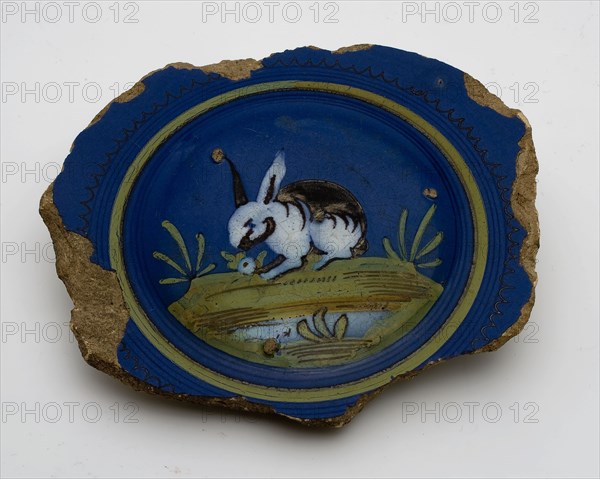 Fragment majolica pancake plate with rabbit or hare on dark blue background, plate crockery holder soil find ceramic earthenware