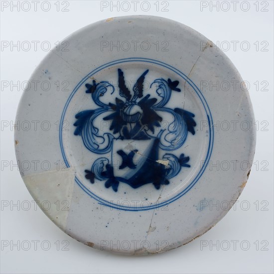 Faience plate on stand surface, decoration coat of arms with winged helmet in blue on white background, plate crockery holder