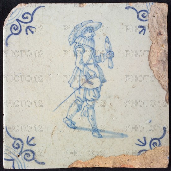 White tile with blue warrior with bird on arm and plume hat; corner pattern ox head, wall tile tile sculpture ceramic