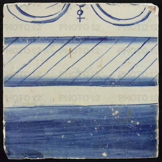 Tile, blue on white, border with filled part and part with hatching, top edge visible part of bow and ball with cross, tile