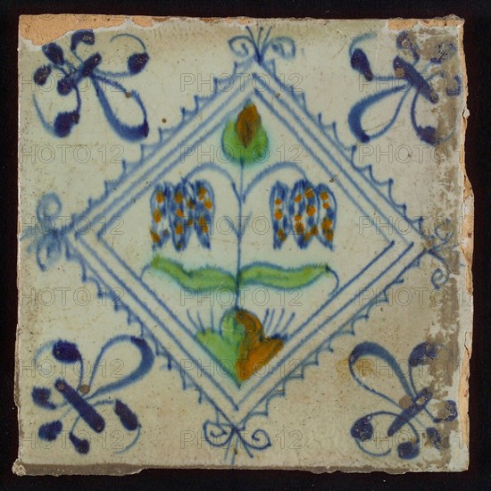 Tile, double flower on ground in orange, green and blue on white, inside serrated square with plume, corner pattern french lily