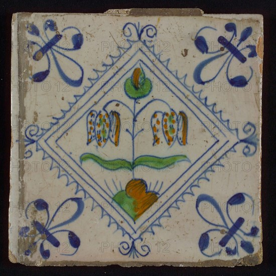 Tile, double flower on ground in orange, green and blue on white, inside serrated square with plume, corner pattern french lily