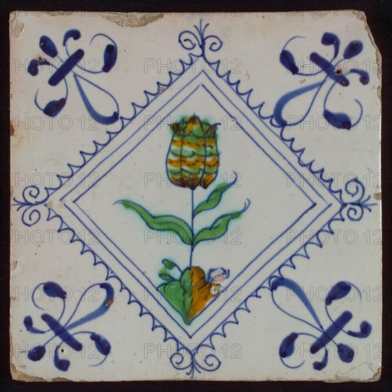 Tile, tulip on ground in orange, green, purple and blue on white, inside serrated square with plume, corner pattern french lily