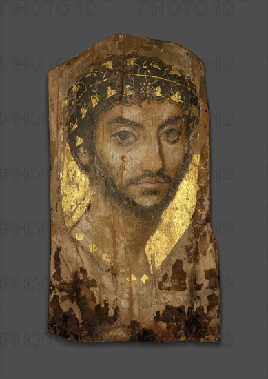 Mummy Portrait of a Man Wearing an Ivy Wreath, Early to mid–2nd century AD, Roman, The Fayum, Egypt, Fayum, Lime (linden) wood, beeswax, pigments, gold, textile, and natural resin, 39.4 × 22 × 0.2 cm (15 1/2 × 8 5/8 × 1/16 in.), depth with support 3.5 cm (1 3/8 in.)