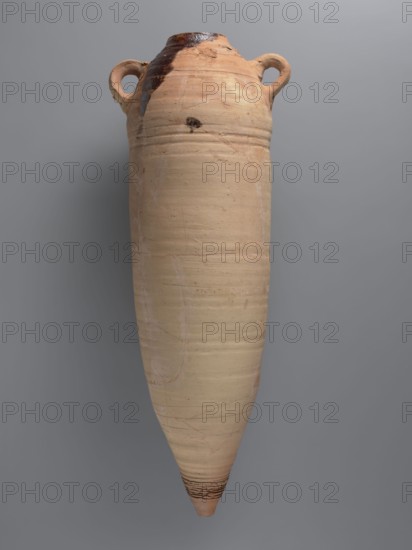 Amphora, unknown Gazan workshop Gaza Strip place of manufacture; Large LRA 4 amphora of a spindle-shaped form, almost cylindrical in the central part. Hemispherical shoulders, conical flat-topped bottom. Rim weakly accentuated, rounded, with slightly thickened edge. Two loop handles placed in the upper part; lower parts reinforced with clay underpinning. Ceramic fabric likely contains limestone inclusions particles visible on surface. Outer surface beige-orange, upper part covered with slipped/soaked clay to obtain a rough surface. Ribs visible in upper and lower parts; deep grooves in the bottom part. Interior coated with black resin impregnation, some of which has leaked onto the shoulder. Near one handle a small, barely visible Coptic inscription in black ink; a large inscription in red paint runs along the vessel. Probably 4th quarter of the 6th–7th century. Find location: Edfu. Vessel type: amphora. Dimensions: height 75.3 cm; rim diameter 10.0 cm; body diameter 23.6 cm; bottom di...