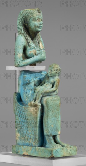 Figurine of the goddess Isis nursing Horus; maker, Harpocrates myth., Isis myth.; Egyptian deities, female figurines, Egyptian art; 664–332 BC, Late Period, Egypt; figurine, A turquoise-colored seated female figure wearing a braided headdress and a beaded collar holds her arms crossed over her chest while a smaller turquoise child figure sits on her lap; the figures rest on a patterned throne with a textured scale-like design on its side and a rectangular base, and the object shows areas of lighter and darker turquoise with patches of greenish and brown discoloration and some worn spots.