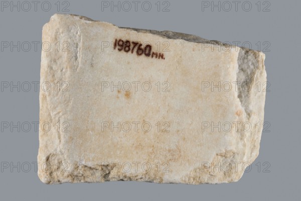 Euphemia's Epitaph, Greek inscriptions, tombstone epitaph. Preserved central fragment of a white marble slab; top and bottom chipped, inscription intact. In the center a large cross with almost equal arms widening at the ends; the inscription is placed between the arms. Rounded letters placed between marked thin lines; letter height 1.5–2.1 cm, average line spacing 0.2 cm. Origin: Bithynia or Constantinople, 6th–7th century, Asia Minor. Stele; height 15.0 cm, width 20.5 cm, depth 3.2 cm., A roughly rectangular slab with a rough, uneven surface and broken edges, showing a pale off-white to beige stone with areas of light tan and small darker spots, set against a solid gray background.