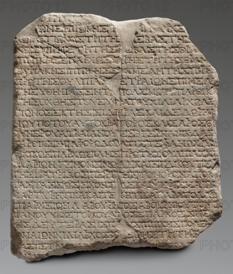 Honorific inscription, unknown workshop of Asia Minor author, repossession, Roman legions, military decorations, 120–130, Asia Minor Heraclea Salbake, inscription; height 57 cm, width 49 cm, depth 8 cm, weight 49.5 kg, A roughly rectangular stone slab with an irregular top and chipped edges, showing a weathered, uneven surface and a vertical crack near the center; the slab is light beige to pale gray with darker gray shadowing in recessed areas, and there are subtle warm tan and brown patches on parts of the surface; the face of the slab is covered by a grid-like pattern of shallow carved horizontal lines and repeated short carved marks within those lines, creating a textured, incised appearance; overall the stone sits against a smooth neutral gray background.