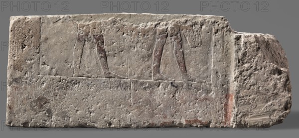 Fragments of wall decoration from the mastaba of the dignitary Tepemankh, Niuserre ruler of Egypt; ca. 2445–2421 BC, Tepemankh ca. 2445–2421 BC, revindication provenance, sacrificial artists, scribes, mastabas, shipwright iconography, Scen.Gal.Eg., Egyptian architecture, sepulchral funerary architecture, scenes of boat building and bringing funerary offerings, c. 2445–c. 2421 BC; Old Kingdom, 5th Dynasty Nyuserre's reign, Abusir, bas-relief, height 26 cm, width 302 cm, depth 16 cm, weight 140 kg, A rectangular stone block with a rough, pitted surface shows a carved scene of two pairs of human legs in profile, with the legs arranged horizontally on a slightly raised band; the carved limbs have traces of reddish-brown pigment while the rest of the stone ranges in pale beige and light gray tones with areas of darker gray discoloration and small patches of muted red.