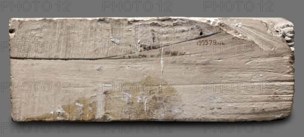Fragments of wall decoration from the mastaba of the dignitary Tepemankh. Niuserre ruler of Egypt; ca. 2445–2421 BC. Tepemankh ca. 2445–2421 BC. Scenes of boat building and bringing funerary offerings; sacrificial artists, scribes, shipwright iconography. Egyptian sepulchral funerary architecture; mastaba. Old Kingdom, 5th Dynasty Nyuserre's reign, c. 2445–c. 2421 BC. Abusir. Bas-relief. Height 26 cm, width 302 cm, depth 16 cm, weight 140 kg., A rectangular slab with a rough, textured surface showing areas of scraping and chipping in shades of beige, off-white, tan, and light brown, with small patches of darker brown and white residue; the slab has worn edges and irregularities, a few small holes and indentations, some vertical and diagonal score marks, and a few streaks and smudges of lighter off-white against a muted gray background.