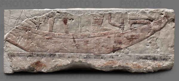 Fragments of wall decoration from the mastaba of the dignitary Tepemankh; Niuserre ruler of Egypt; ca. 2445–2421 BC, Tepemankh ca. 2445–2421 BC., Iconography: sacrificial artists, scribes, mastabas, shipwright; scenes of boat building and bringing funerary offerings. Egyptian, sepulchral funerary architecture; Scen.Gal.Eg., Egyptian architecture. Date: c. 2445–c. 2421 BC, Old Kingdom, 5th Dynasty Nyuserre's reign. Place of origin: Abusir. Medium: bas-relief. Dimensions: height 26 cm, width 302 cm, depth 16 cm; weight 140 kg., A carved stone relief showing a long boat shape with a curved prow and stern, shallow hull details, and the suggestion of people through carved arms and hands holding poles; the surface has worn carved lines and shallow incisions outlining the boat and figures. The stone shows a palette of pale off-white and beige with areas of reddish-brown pigment on the boat and some brownish spots and smudges across the surface, plus darker grayish marks along a lower band. Th...