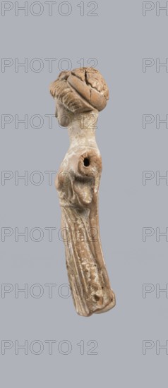 Terracotta figurine of a woman, terracotta, female figurines, molded figurines, Greece, dolls, orange clay, surface covered with whitewash. Terracotta figurine of a woman dressed in a short, pleated chiton girdled at the waist. Long, thick neck and disproportionately small head with an oval face. Hair combed upwards and tied in a bun, held in place by a headband tenia tied in a bow at the top of the head. The back of the figurine is unfinished. The figurine originally had separately attached arms and legs below the knees, as evidenced by a special recess and perforations for hooks. Condition: missing arms and legs, whitewash worn away. c. 400 BC, Greece, toy, height 10.1 cm, width 3.5 cm, A weathered beige-brown terracotta figurine of a standing woman shown in profile against a flat pale gray background, with a rounded head wrapped in a textured bun, a delicate facial profile, a long slender neck, a draped garment with vertical folds running down the length of the body, an arm stump wi...