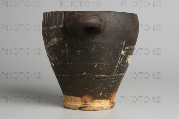 Black-finished skyphos with painted decoration on the finis, white decoration: A = B - laurel branch, IV waC, Etruria, vessel, height 9.7 cm, width 9.2 cm, A worn dark brown clay vessel with a rounded body tapering to a lighter beige base, showing a few faded pale markings and scuffs on its surface, a short protruding handle near the rim, and a smooth gray background.