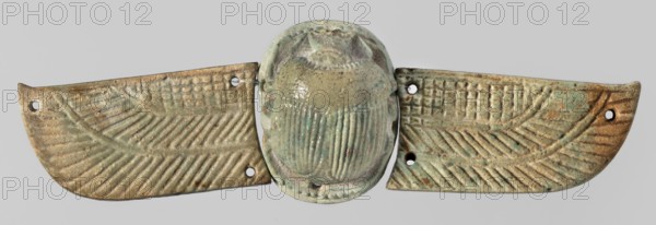 Winged scarab. Winged scarab with a realistically modeled torso, head, and legs. On the outstretched wings, imitating plumage, is an ornament consisting of a grid-covered field and two stripes covered with diagonal lines. The small oval base on which the scarab is placed has six holes for attachment to a mummy net. There are three similar holes on each wing. Due to the non-corresponding holes on the sides of the scarab and on the inner part of the wings, it can be assumed that they were not originally a single piece, but were fitted together later for antiquarian purposes. 664–332 BC Late Period, Egypt. Amulet scarab. Height 3.4 cm; width 12.5 cm., A horizontal decorative object with a central raised rounded element flanked by two wing-shaped panels, all showing a textured carved pattern of parallel ridges and grooves. The central piece has a ribbed vertical pattern and a scalloped edge where it meets the panels, and the panels each have a feather-like carved motif with a grid-like tex...