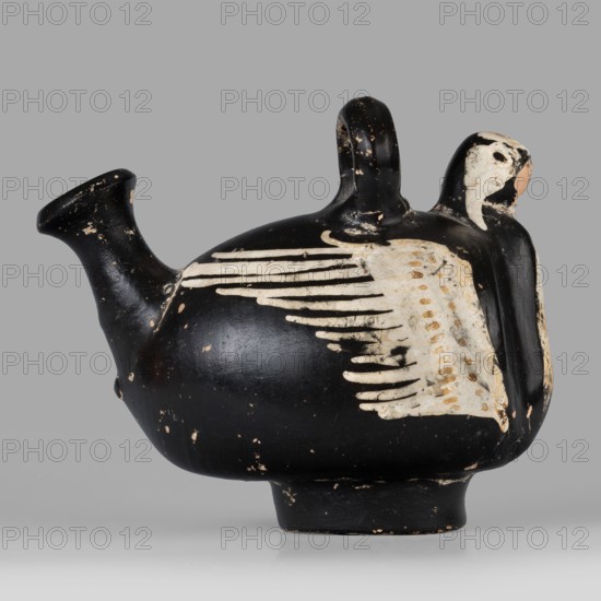 Guttus gnathia in the shape of a bird, bird with wings iconography, southern Italic pottery, Apulia; end of 4th–beginning of 3rd century BC ca. 300 BC; guttus vessel; height 9.5 cm, width 6.4 cm, depth 11.3 cm, weight 0.164 kg, A rounded ceramic vessel shaped like a bird with a short spout and a curved handle, showing worn black and white painted surfaces with a few areas of beige and light brown, a group of white feather-like strokes along the side, a stylized bird head at one end with a white face and black eye area, small chips and abrasions revealing underlying material, and a plain gray background.