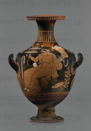 Red-figure hydria, Southern Italy, Apulia; hydria vessel, 330–320 BC. Black glossy engobe with some elements painted white. Red-figure hydria on a high, profiled foot with slightly sloping shoulders; narrow neck widening toward the rim; wide flat rim rolled outward and decorated with vertical-line ornamentation. Three handles: two vertical below the shoulders and one horizontal from the rim to the shoulders. Palmettes beside the handles. Frontal-belly scene: a woman seated on a rock wearing a long chiton; in her right hand she holds two flowers, in her left a kalathos and a wreath. A plate lies on the ground behind her, and a rolled-up cloth hangs in front of her., A painted ceramic vessel with a rounded body, narrow neck, flared lip, and a pedestal foot, shown against a neutral gray background. The vessel has a pair of small curved handles near the shoulder. The surface decoration includes a central figural scene painted in a warm terracotta color against a largely black ground, with ...