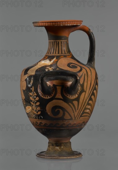 Red-figure hydria, Southern Italy Apulia. Hydria vessel, 330–320 BC. Black glossy engobe with some elements painted white. On a high, profiled foot with slightly sloping shoulders; narrow neck widening toward a wide, flat, outward-rolled rim decorated with vertical-line ornamentation. Three handles: two vertical below the shoulders and one horizontal from rim to shoulders. Palmettes beside the handles. Frontal belly scene: a seated woman on a rock wearing a long chiton; in her right hand two flowers, in her left a kalathos and a wreath. A plate lies behind her on the ground and a rolled-up cloth hangs in front of her., A painted ceramic vessel with a rounded body, narrow neck, flared rim, and a single curved handle, displayed against a neutral gray background; the surface shows decorative painted motifs including sweeping spirals, stylized leaf and floral patterns, and banded designs in contrasting colors. The vessel's color palette includes terracotta orange, black, and lighter beige ...
