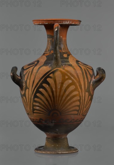 Red-figure hydria, Southern Italy, Apulia Italy. Hydria vessel with black glossy engobe and some white-painted elements. On a high, profiled foot with slightly sloping shoulders; narrow neck widening toward a wide, flat, outward-rolled rim decorated with vertical-line ornamentation. Three handles: two vertical below the shoulders and one horizontal from rim to shoulders; palmettes next to the handles. Frontal belly scene: a seated woman on a rock, wearing a long chiton, holding two flowers in her right hand and a kalathos and a wreath in her left; a plate lies behind her and a rolled-up cloth hangs in front. Dated 330–320 BC., An orange-brown ceramic vase with black painted patterns sits against a gray background; it has a flared rim, a narrow neck, a rounded body on a pedestal foot, and three handles with curved shapes. The surface shows stylized black fan-like and curving motifs radiating across the body, darker black areas near the base and neck, and small areas of wear where lighte...
