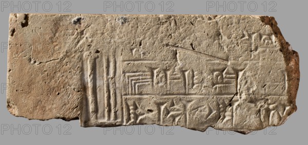 Fragment of a brick with a cuneiform inscription, architectural element, cuneiform writing, Near Eastern architecture, Nebuchadnezzar II 604–562 BC, Eastern Gallic Scenography, ca. 604–ca. 562 BC, Babylonia, Borsippa, brick; weight 534 g; height 6 cm; width 15 cm; thickness 5 cm., A rectangular stone slab with an irregular broken edge, showing a rough, pitted surface and carved shallow grooves and linear incisions arranged in geometric groupings across its face; the stone displays a range of beige, tan, sandy brown, and pale gray tones with small darker brown and gray specks and patches; several vertical and horizontal groove groups create stepped and angular patterns, and a few shallow rounded indentations and chips appear along the perimeter, with one corner more jagged and eroded than the rest.