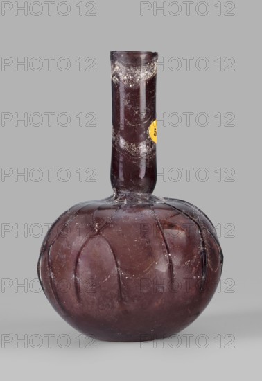 Bottle with a spherical belly, unknown eastern workshop; translucent manganese glass; spherical belly decorated with applied thread decoration in the shape of the letter X; long cylindrical neck with a narrowing at the bottom; uneven, cold-worked rim; free-blown; 3rd century; vessel; rim diameter 2.35 cm; base diameter 3.2 cm; weight 0.062 kg., A single glass vessel with a bulbous rounded base and a long narrow neck, shown against a plain light gray background; the glass appears dark purple to deep maroon with areas of lighter and darker shading and a slightly glossy surface; the rounded body has vertical rib-like grooves creating a segmented appearance and shows some surface irregularities and small white speckled deposits; the neck is straight and cylindrical with a few cloudy patches and the glass surface shows signs of wear and tiny scuffs; a small circular colored sticker is partially visible on the neck.