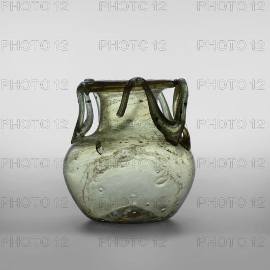 Flask, unknown eastern workshop, glass vessels, miniature vessels, Type: Barag type VI:9 Transparent glass, yellowish-green with applied thread decoration between the arms and the rim edge in the form of 10 sharp bends; free-blowing Outer diameter of the rim: 5.50 cm Bottom diameter: 3.90 cm, 4th century, Roman Empire 27 BC–476, vessel, weight 0.076 kg, A translucent glass vessel with a rounded body and a narrow flaring neck, showing a greenish hue with areas of pale green and olive tones; the rim is encircled by a darker green applied looped decoration that forms several curved handles draping down the neck, and the glass surface contains a few visible bubbles and streaks as well as some cloudy, textured deposits and surface irregularities; the object sits on a neutral gray surface against a light gray background.