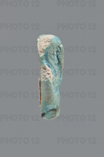 Shabti, Mummy-shaped funerary figurine, legs missing. Arms crossed on the chest, hands invisible under the shroud. Wears a long, smooth, three-part wig; beard is wide, straight, and smooth. Not inscribed. Late Period, Egypt, 664–332 BC. Height 3.8 cm., A single irregular vertical object with a rough, porous surface in shades of turquoise and light blue, with areas of pale beige and off-white where the material appears crumbly, and small dark grayish-green patches near the lower edge; the object has uneven contours and textured cavities, and it is set against a uniform medium-gray background.