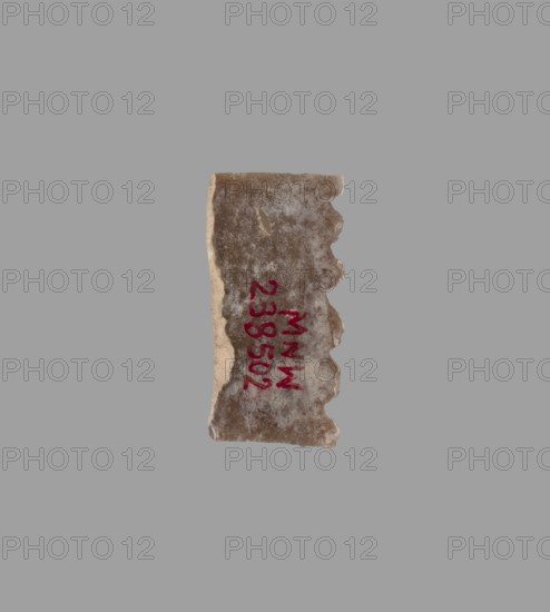 Blade — insert for a sickle;, Flint tool used as a sickle insert. Uruk culture, Southern Mesopotamia Sumer, 4th–3rd millennium BC. Tool; material: flint., A small irregular fragment with a rough, textured surface in shades of beige, brown, and gray sits against a solid medium gray background; the fragment has one straight edge and an opposite scalloped edge with a series of rounded indentations, and a vertical streak of darker brown runs along its center while the edges show lighter beige tones.