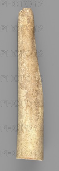 Mosaic cone, mosaic cones, decorative element used in decoration of facades of cult buildings; Sumer, Southern Mesopotamia; element of architectural decoration; 2nd half of the 4th millennium BC Uruk Culture, ca. 4000–ca. 3100 BC;, A single elongated cylindrical object photographed upright against a plain background, appearing tapered and rounded at the top and slightly wider and flatter at the bottom; the surface shows a rough, grainy texture with irregular patches and speckles; visible colors include beige, tan, light brown, off-white, and hints of gray; the background is a uniform medium gray.
