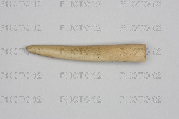 Mosaic cone, decorative elements, Uruk culture ca. 4000–ca. 3100 BC, mosaic cones, Sumer, Uruk Warka, Iraq, 2nd half of the 4th millennium BC, Sumer, Southern Mesopotamia, architectural decoration, diameter 1.2 cm, length 7.7 cm, A single elongated object with a tapered end lies horizontally against a light gray background; the object is mostly beige with subtle variations of tan and light brown, showing a few darker speckles and faint reddish areas near the tapered tip, and its surface appears smooth with slight texture.