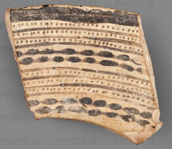 Fragment of a bowl, unknown Northern Mesopotamian workshop, painted pottery, geometric motifs, bowls, Near Eastern pottery, Eastern Gaulish Scene. Fragment of a bowl wall with a preserved thin rim edge and a transition to a flat, bottom. Before firing, the decoration consisting of geometric motifs was painted with ferrous clay on both sides of the bowl, over a layer of dry, very smoothed glaze. After firing, the painted decoration ranged in color from red to dark brown, while the background is shiny and cream-colored. The geometric motifs on the interior consist of groups of horizontal continuous and dotted lines, alternating with double lines, on which are placed small, elongated ovals. On the outer side, the decoration is a striped composition consisting of groups of several parallel diagonal lines inclined alternately to the left and to the right, and alternating triangular fields where the diagonal lines meet. Ca. 6500–ca. 5500 BC; Halaf culture, Northern Mesopotamia Iraq, Syria, T...