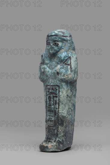 Ushabti Amenmose, Hieroglyphs, funerary figurine mummy-shaped shabti. Arms crossed on the chest, right folded over left; hoes in both hands; a basket on the back. Smooth tripartite wig with headband; ears uncovered; large eyes; mouth and nose not distinct. Tools, facial details, and headband painted with dark paint. Painted inscription in a column of text enclosed in a frame: Osiris the prophet of Amun Amenmose, justified by the voice. c. 1069–c. 656 BC, Third Intermediate Period, Egypt. Height 16.4 cm; width 5.3 cm., A small upright figurine with a weathered surface in shades of blue and turquoise with areas of darker teal and pale green, standing on a grayish base; the figure has a rounded head and a simplified face with darker markings around the eyes and hair, a short rounded torso with raised arms held close to the chest, and a long narrow lower body that tapers toward the feet, showing patches of darker blue and black discoloration and worn lighter spots.