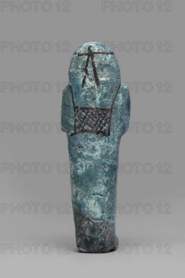 Ushabti Amenmose., Warmian-Masurian Voivodeship. Hieroglyphs, funerary figurine, wig, grave good, mummy-shaped figurine. Arms crossed on the chest, the right folded over the left. Hoes in both hands. A basket on the back. On the head is a smooth, tripartite wig with a headband. Ears uncovered. Large eyes; mouth and nose not distinct. Tools, facial details, and the headband painted with dark paint. Painted inscription placed in a column of text enclosed in a frame: Osiris the prophet of Amun Amenmose, justified by the voice. c. 1069–c. 656 BC, Third Intermediate Period, Egypt. Type: shabti. Height 16.4 cm, width 5.3 cm., A small sculpted figure viewed from the back, rendered in mottled blue-green with areas of darker teal and pale turquoise, standing against a plain light gray background. The figure has a rounded head and narrow shoulders with faint arm shapes at the sides, and the surface shows rough, pitted texture and worn spots with hints of darker bluish-black at the base. There ar...