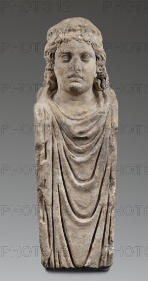 Double herm with heads of Apollo, unknown Roman workshop; herms; Apollo myth.; Roman sculpture, Antonine period 138–192; Roman Empire 27 BC–476; sculpture; height 67 cm, width 27 cm, depth 24 cm, weight 85.5 kg, A carved stone bust of a person with long wavy hair and a neutral facial expression, shown from the head down to a draped garment; the stone surface is weathered with rough texture and worn details, and the visible colors are beige, light brown, gray, and off-white against a neutral gray background.