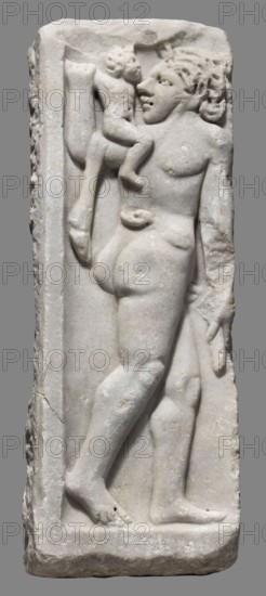 Fragment of a sarcophagus, unknown Roman workshop, end of the 3rd century, Roman Empire 27 BC–476, sarcophagus, height 47 cm, width 16.5 cm, depth 9 cm, weight 15 kg, A carved pale stone relief showing a standing adult figure seen from behind and in profile, holding a small child perched on the adult's shoulder; the adult has detailed carved hair and facial features and the child has a rounded head and limbs; both figures are nude and are depicted within a recessed rectangular panel; the stone surface is light gray with subtle variations and small patches of darker gray and beige, and the background behind the relief is a uniform medium gray.