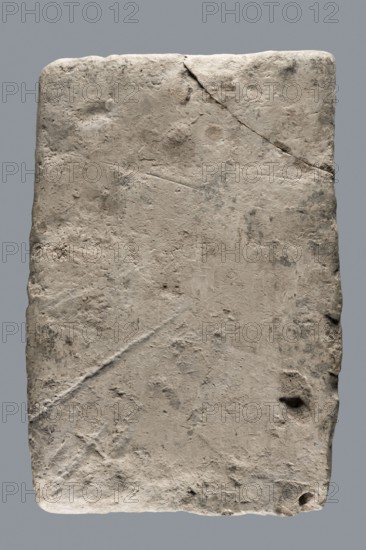 Greek inscription of thanksgiving, tombstone inscription, 30.12.23 BC, Egypt, Greek inscription, height 24.0 cm, width 14.0 cm, depth 5.8 cm, A rectangular slab with rounded corners showing a rough, pitted surface in shades of light gray, beige, and off-white, set against a uniform gray background; the slab has visible cracks, scratches, and small indentations, with darker gray and brownish smudges and spots scattered across its face, and slightly darker, irregular edges that suggest wear.