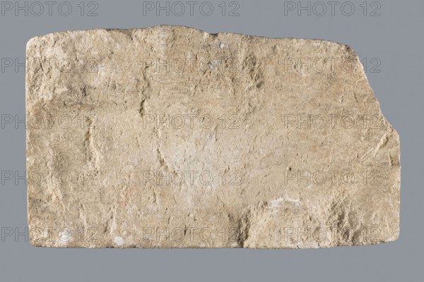 Slab with a Latin votive inscription for Fortuna Conservatrix, Caius Iulius Maianus commissioner, Fortuna mythology, Latin inscriptions, baths, centurions, Germania Superior province, Roman legions. Limestone slab with a smoothed front surface and sides and a rather irregular back; upper left corner missing. Front surface carved with a 5-line inscription; letters were at one time outlined with red paint two types: darker in most letters and a lighter, very thick paint in the letter E in the second line. Dated 130–259/260. Type: slab, votive inscription. Dimensions: width 33 cm, height 18 cm, thickness 6 cm. Found at Bad Ems presumably in the baths of the Roman fort., A roughly rectangular stone slab with an irregular top edge sits against a flat gray background; the slab surface shows a rough, pitted texture with worn, uneven areas and small depressions, and its color palette includes beige, tan, light brown, off-white, and hints of pale gray, with a few slightly darker brown patches a...