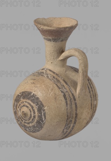 Cypriot gourd jug, Excavated at Nea Paphos Cyprus. Cypriot pottery, Cypriot Bichrome Ware III. Small vessel with a barrel-shaped gourd-shaped body, without a foot, with a spherical bottom. On both shorter sides the center is marked with a small protruding point. A single ring-shaped handle on the longer side, mounted above half the height of the body and at the base of the neck, curved downwards. Quite long neck, strongly flaring, conical spout. Yellow clay with yellow-brownish engobe. Decoration in black-brown and matte red: spout externally with a wide matte red band beneath a narrower black band; belly decorated on both sides with two groups of three concentric black-and-brown lines of varying widths and spacing in groups on the shorter sides the outer line is much wider. Protruding points are marked in black-and-brown. Dated 850–700 BC. Vessel from Cyprus., A rounded clay vessel with a narrow neck and flaring rim, featuring a curved handle that connects the neck to the shoulder; th...