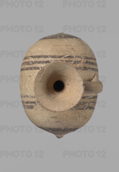 Cypriot gourd jug, Excavations at Nea Paphos Cyprus. Cypriot pottery, Cypriot Bichrome Ware III. Small vessel with a barrel-shaped gourd-shaped body, without a foot, with a spherical bottom. On both shorter sides the center is marked with a small protruding point. A single ring-shaped handle on the longer side, mounted above half the height of the body and to the base of the neck, curved downwards. Quite long neck, strongly flaring, conical spout. Yellow clay with yellow-brownish engobe. Decoration in black-brown and matte red: the spout is decorated externally with a wide matte red band beneath which is a narrower black band; the belly is decorated on both sides with two groups of three concentric black-and-brown lines of varying widths and spacing, with the outer line in the groups on the shorter sides much wider than the others. Protruding points are marked in black-and-brown. 850–700 BC, Cyprus, vessel., An oval ceramic vessel viewed from above with a rounded body and a central fun...