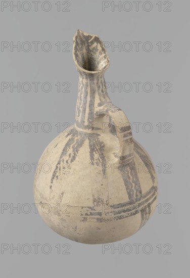 Jug, Excavated at Nea Paphos Cyprus. Cypriot pottery, Bronze Age White Painted IV, dated 1800–1650 BC Middle Cypriot period II–III. Cream clay with cream surface; geometric decoration in black. Pear-shaped belly, tall tapering neck, three-part spout, gently rounded base. Small vertical ribbon-like handle vise placed in an arc above the base of the neck; handle exterior decorated with three groups of three transverse lines each and painted sides; interior of spout similarly decorated. Neck covered with densely spaced straight and wavy lines, terminating at a horizontal line at the neck base. Upper body decorated with eight sets of two wavy lines radiating from the neck base, bordered by straight lines, extending to about one-third of the body height where they meet three horizontal lines at the vessel’s maximal bulge. Lower body shows four sets of three lines branching from these horizontals toward the base, irregularly spaced and angled. Good condition: two small rim fragments missing ...