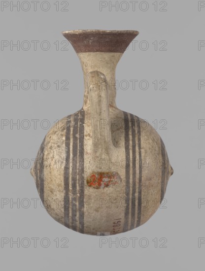 Cypriot gourd jug, A small vessel with a barrel-shaped gourd-shaped body, without a foot, with a spherical bottom. The center is marked with a small protruding point on both short sides. A single handle on the long side, mounted at the greatest bulge of the body and at the base of the neck, bent at a right angle. Quite long neck, strongly flaring, conical spout. Neck and handle slightly offset from the vessel axis; the handle is mounted at a slight angle, with a very clear trace of finger pressure on the right side where it is attached to the neck. Reddish-brown clay. Yellowish-brown engobe. Decoration in black-brown and matte red. The rim is decorated externally with a wide matte red band. The body is decorated on both sides with two groups of three concentric black-brown lines, of varying widths and spacing. In the groups on the shorter sides, the outer line is much wider than the others. Protruding points are marked in black-brown. Preservation condition: cracked and glued neck and ...