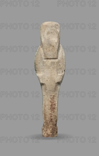 Ushabti, Mummy-shaped funerary figurine standing on a base, the back supported by a flat pillar. Arms crossed on the chest with hands visible from under the shroud; right hand slightly above the left. Left hand holds a pickaxe, right hand holds a hoe and a string from which a basket is slung over the left shoulder. Convex tools. Smooth three-part wig; triangular face with clearly marked large eyes, wide nose, mouth in a slight grimace. Not inscribed. Late Period, 664–332 BC, Egypt. Shabti; height 9.3 cm, width 2.5 cm., A vertical, elongated stone object with a rounded top and tapered lower section, shown against a plain gray background. The surface of the object is rough and weathered, displaying mostly beige and light tan tones with small patches of darker brown and faint greenish discoloration. The silhouette suggests a slightly wider midsection with subtle indentations along the sides and a flattened upper area. There are areas of reddish-brown staining on the lower portion and some...