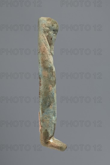 Ushabti, Mummy-shaped figurine, funerary gift, hoes. Very schematically shaped; hands crossed on the chest. Long tripartite wig on the head. Facial details illegible. Not inscribed. ca. 1069–ca. 656 BC, Third Intermediate Period, Egypt. Ushabti; height 9.4 cm., A narrow vertical object resembling a slender leg with a bent foot, shown against a plain gray background, with surfaces that are mottled in shades of green, blue, brown, and beige and areas of rough, pitted texture, along with a small patch of pinkish material on one side.