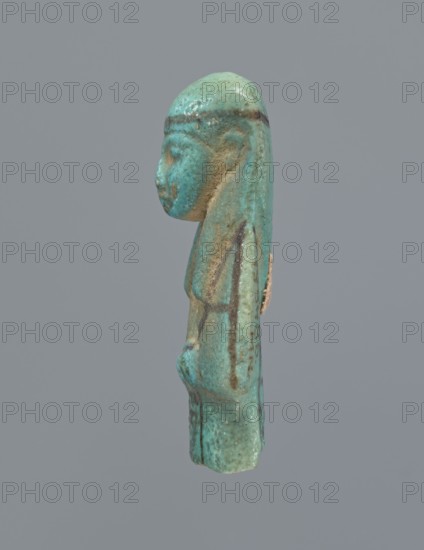 Ushabti, mummy-shaped figurine, preserved upper fragment from the waist up. Arms crossed on the chest, hands placed at the same level, next to each other, holding hoes. Rectangular basket on the back. Long, smooth, three-part wig with a headband; triangular face with proportional details; eyes slightly closed. Headband and facial details painted. Painted inscription in a column separated by vertical lines on the front of the legs, starting just below the folded hands; text illegible. Shabti, c. 945–c. 715 BC, Third Intermediate Period, 22nd–23rd Dynasty, Egypt. Height 5.8 cm., A small sculpted figure shown in profile against a plain gray background, predominantly turquoise with areas of greenish-blue and mottled brown, depicting a human-like head with a smooth rounded top and long hair or headdress that extends down the back; the face has a pronounced nose and chin, a slightly rounded cheek, and a subtle ear shape, with the body beneath showing a narrow torso and arms positioned along ...