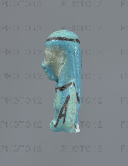 Ushabti, Mummy-shaped figurine, preserved head and fragment of torso. Arms crossed on the chest, hands placed at the same level, next to each other, holding hoes. On the back a rectangular basket is slung on strings over both shoulders. On the head a long, smooth, three-part wig with a headband. Triangular face with proportional details, eyes slightly closed. Headband, tools, and facial details painted. ca. 945–715 BC; Third Intermediate Period, 22nd–23rd Dynasty, Egypt. Ushabti, height 5.2 cm., A small turquoise-blue figurine of a human head and upper torso shown in profile against a plain gray background, with a darker blue-black band across the top of the head and several dark curved markings on the body, a worn and slightly rough surface with patches of lighter and duller blue and some small areas of beige wear, the facial features including a nose and chin visible in profile and the back of the head extending down like a straightened hairstyle or headdress.