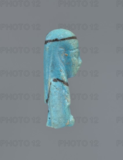 Ushabti, mummy-shaped figurine, funerary gift. Mummy-shaped figurine with preserved head and fragment of torso. Arms crossed on the chest, hands placed at the same level next to each other, holding hoes in each hand. On the back a rectangular basket is slung on strings over both shoulders. On the head a long, smooth, three-part wig with a headband. Triangular face with proportional details, eyes slightly closed. Headband, tools, and facial details painted. ca. 945–ca. 715 BC; Third Intermediate Period, 22nd–23rd Dynasty, Egypt. Ushabti; height 5.2 cm., A small sculpted figure shown in profile against a plain gray background, rendered in a bright blue-green color with areas of lighter and darker blue and small patches of beige; the figure has a smooth rounded head with a dark horizontal band across the forehead and a long straight headdress extending down the back, a defined nose and chin, and a rounded torso with a darker band near the shoulder and some rough textured spots.