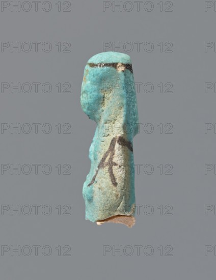 Ushabti, mummy-shaped figurine, preserved head and fragment of torso. Arms crossed on the chest, hands placed at the same level, next to each other, holding hoes in each hand. On the back, a square basket is slung on strings over both shoulders. Wearing a long, smooth, tripartite wig with a headband. Triangular face with details almost illegible. Headband and tools painted. ca. 945–715 BC; Third Intermediate Period, 22nd–23rd Dynasty, Egypt. Ushabti; height 3.7 cm., A small worn figurine fragment shown against a plain gray background, predominantly turquoise in color with areas of pale beige and sandy texture; the piece has a curved head and a vertical, elongated body with rough, weathered surfaces and a few darker brownish marks along the top edge and midsection, and a small exposed beige base at the bottom.